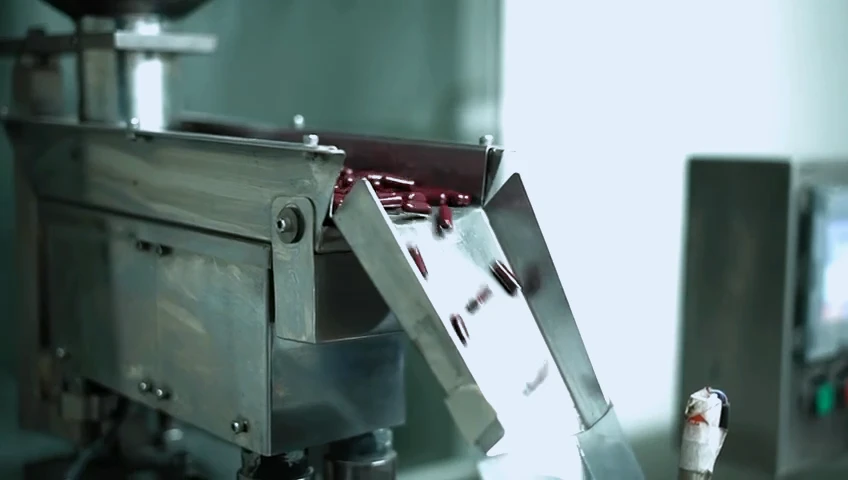 Capsules feeding down the chute of a filling machine